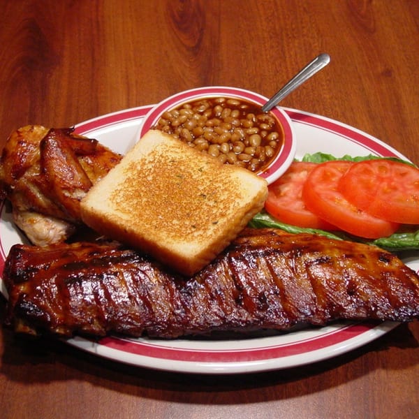 Rib City's BBQ plate with ribs, chicken, baked beans, toast, and a side salad.