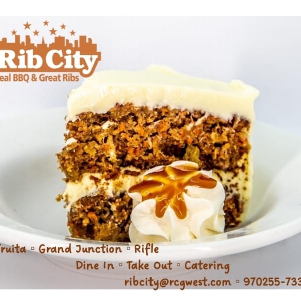 A slice of Rib City's carrot cake with cream cheese frosting and a dollop of whipped cream.