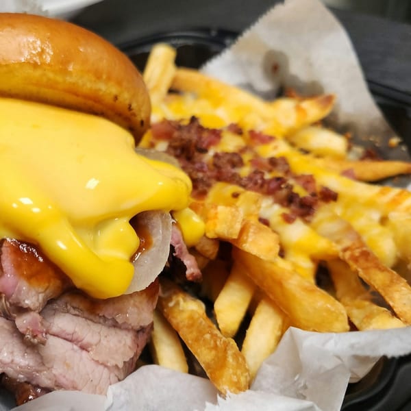 A Rib City BBQ sandwich with melted cheese and onions, served with loaded cheese fries.