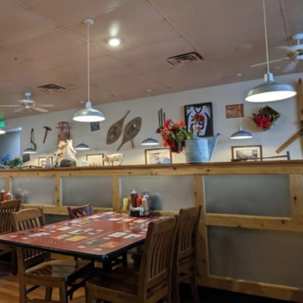 Interior of Rib City restaurant with rustic decor, wooden tables, and chairs, featuring a divider with frosted panels.