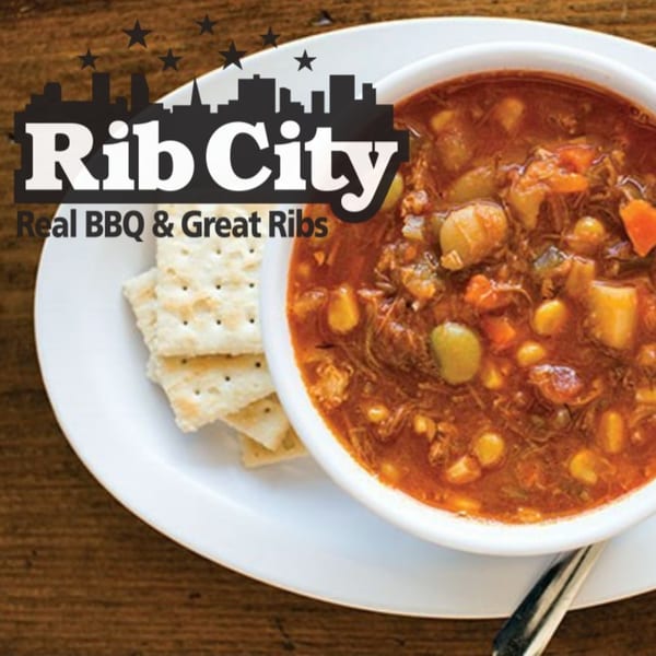 A bowl of Rib City's hearty Brunswick stew with crackers on a white plate.