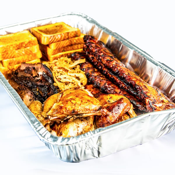 A foil pan filled with Rib City's BBQ ribs, chicken, pulled pork, and Texas toast.