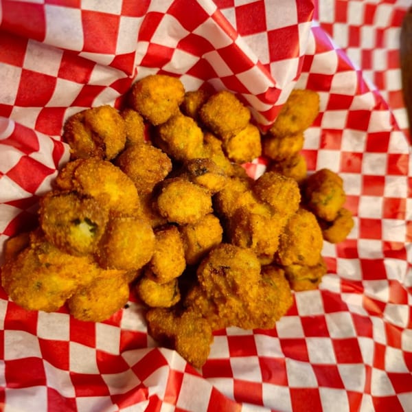A basket of golden-brown fried okra sits on red and white checkered paper at Rib City.