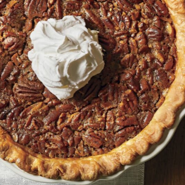 Close-up of a Rib City pecan pie with a dollop of whipped cream on top.