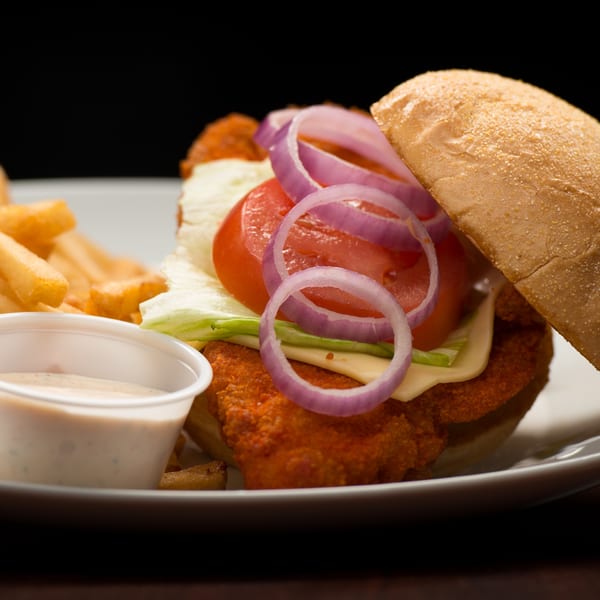 Rib City's crispy chicken sandwich with lettuce, tomato, onion, cheese, fries, and dipping sauce.