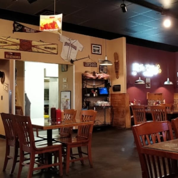 Interior of Rib City restaurant with wooden tables and chairs, baseball memorabilia, and a neon sign.